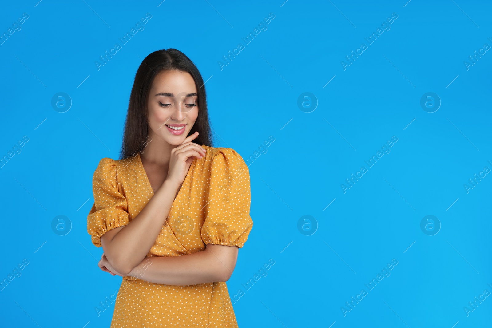 Photo of Young woman wearing yellow dress on light blue background. Space for text