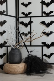 Paper bats and festive decor near white wall. Halloween celebration