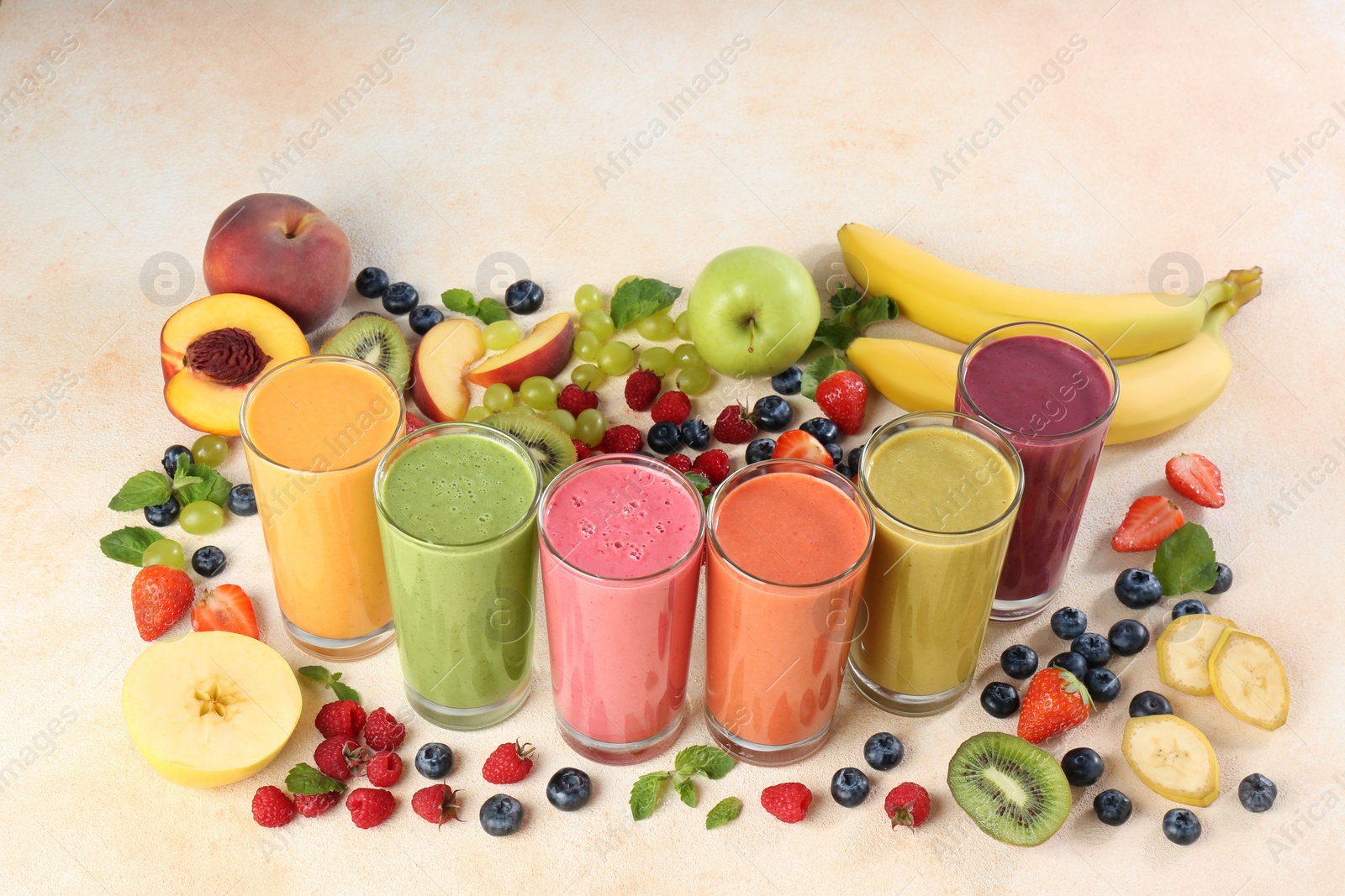 Photo of Fresh colorful fruit smoothies and ingredients on beige table