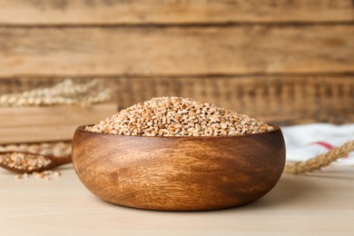 Bowl of wheat grains on white wooden table, closeup