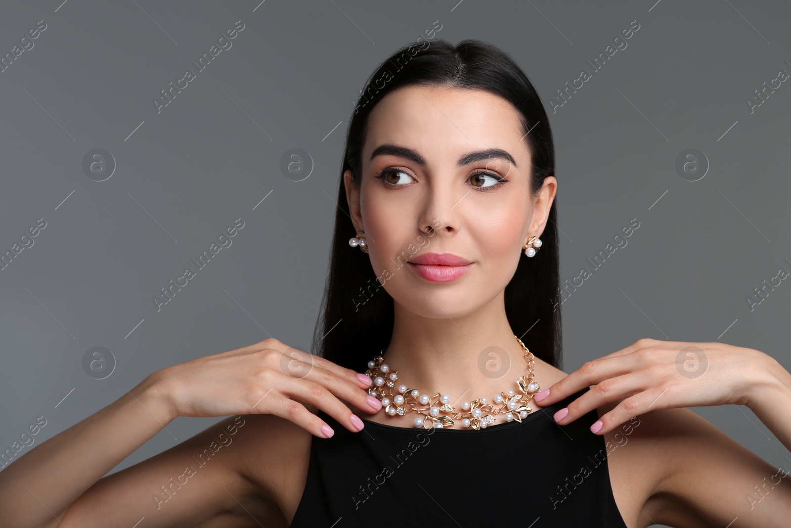 Photo of Beautiful young woman with elegant jewelry on dark grey background