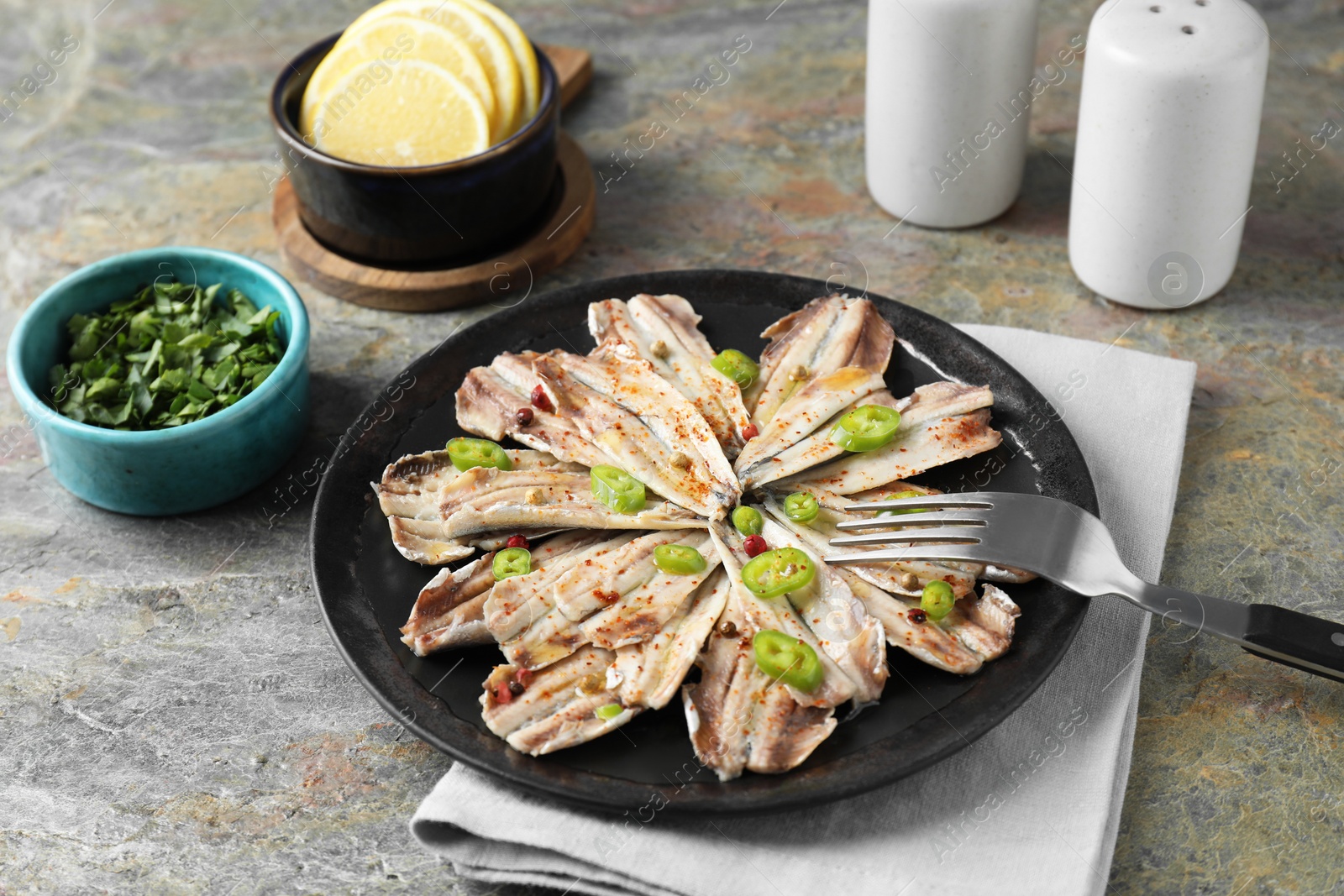 Photo of Tasty pickled anchovies served on textured table