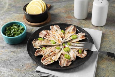 Photo of Tasty pickled anchovies served on textured table