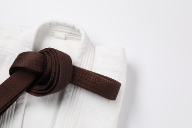 Brown karate belt and kimono on white background, top view. Space for text