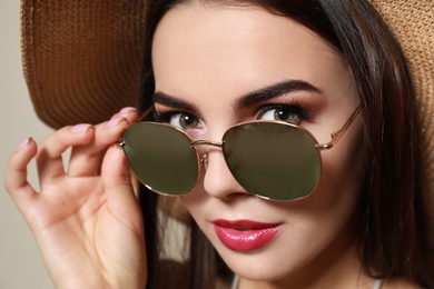 Photo of Beautiful woman in stylish sunglasses and hat on beige background