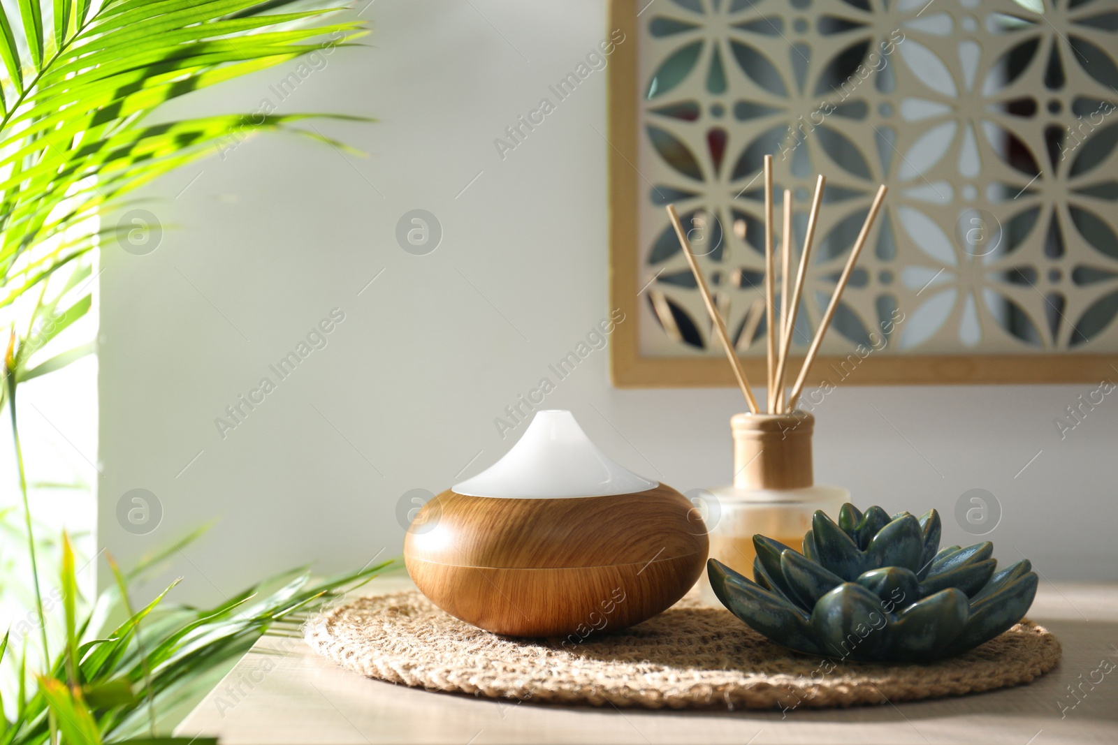 Photo of Aroma oil diffuser and reed air freshener on table in room