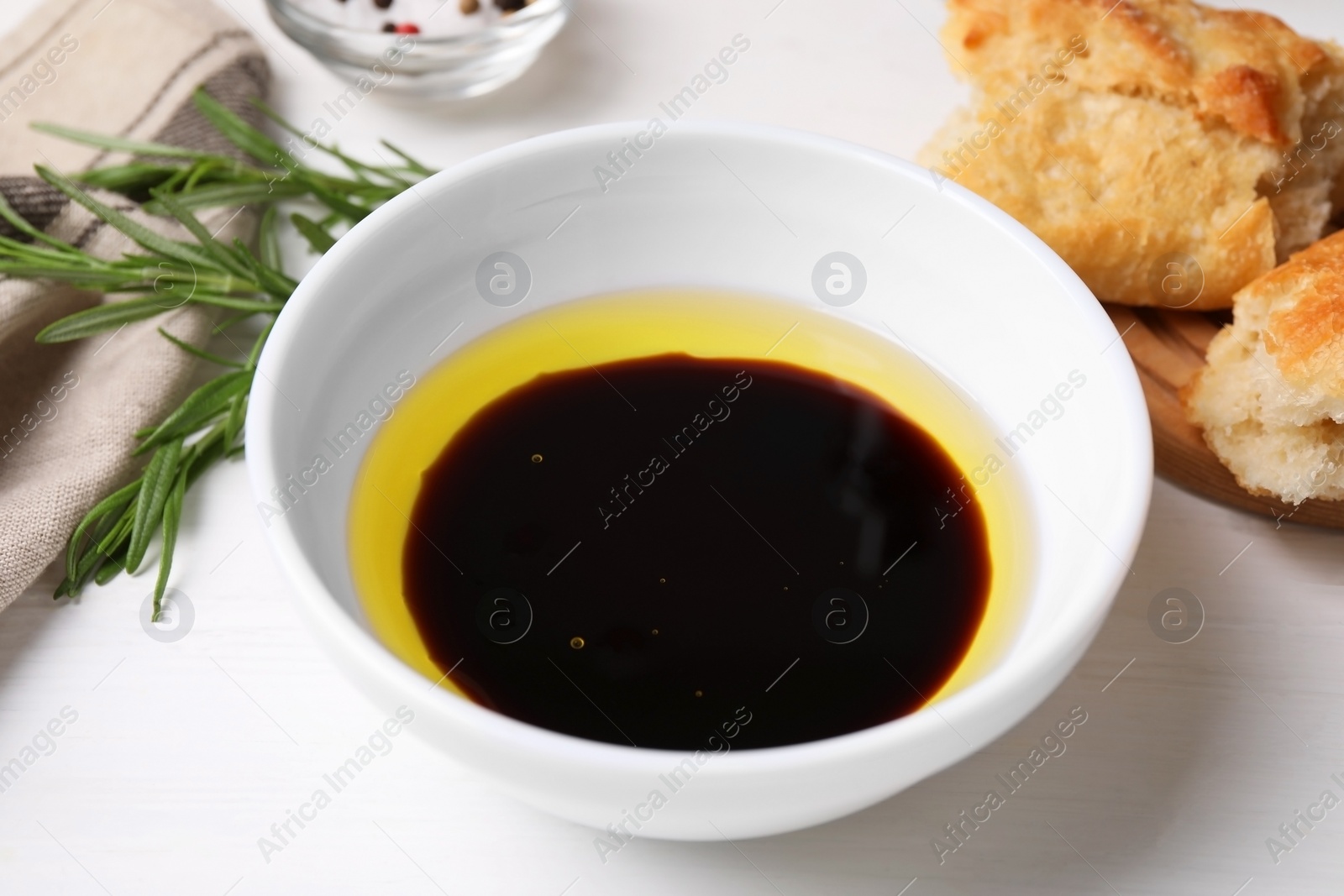 Photo of Bowl of balsamic vinegar with oil on white table, closeup