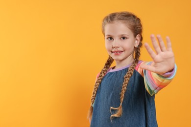 Cheerful girl giving high five on orange background, space for text