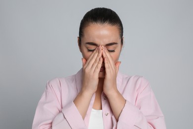 Young woman suffering from headache on light grey background