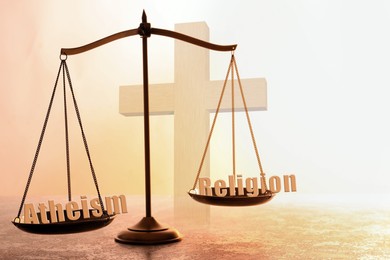 Image of Choice between atheism and religion. Scales with words on textured surface against cross