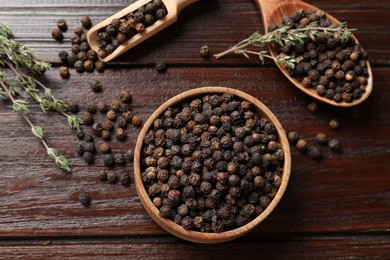 Aromatic spice. Black pepper in bowl, spoon and scoop on wooden table, flat lay