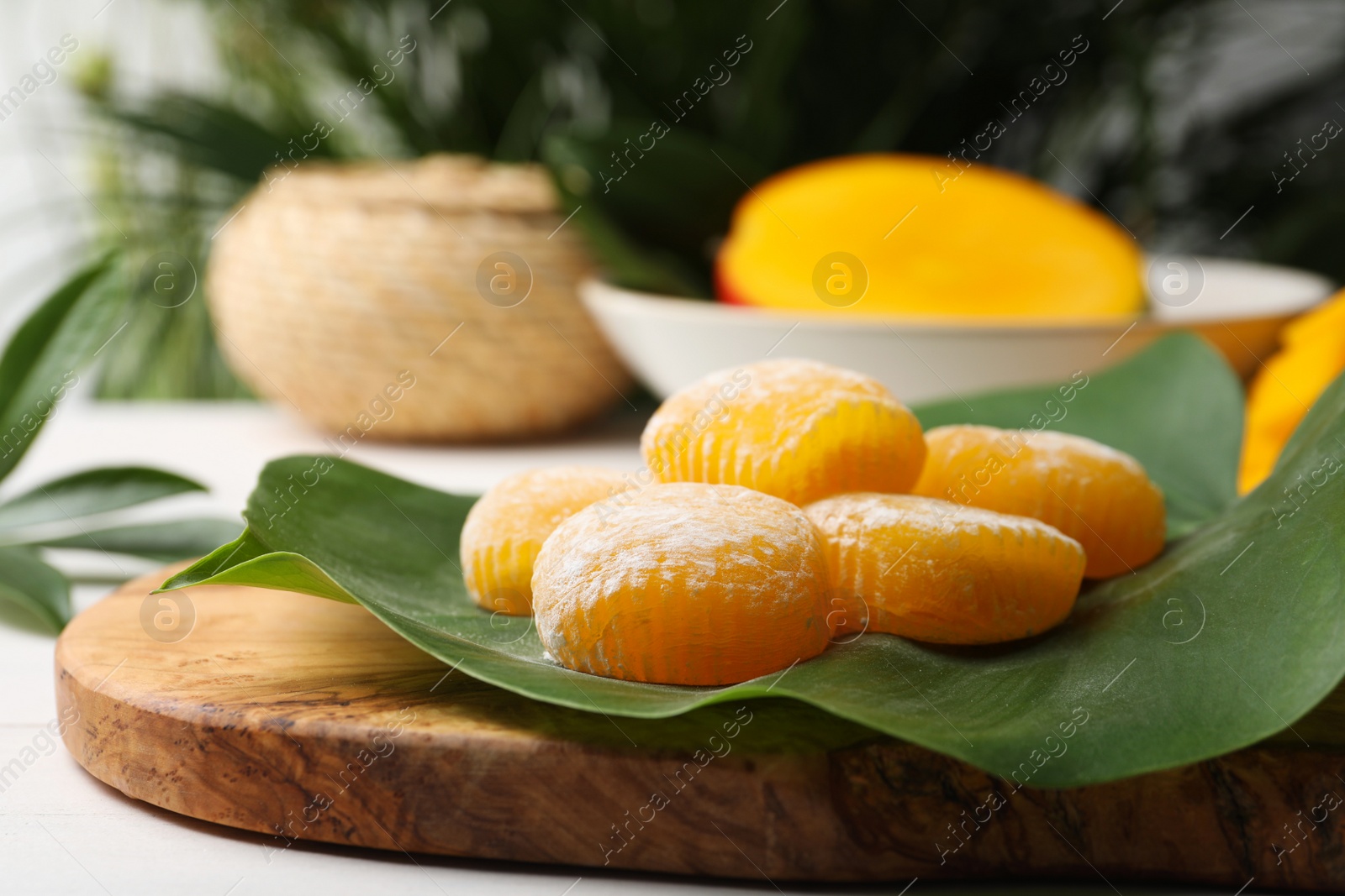 Photo of Delicious mochi with green leaf on wooden board, closeup. Traditional Japanese dessert