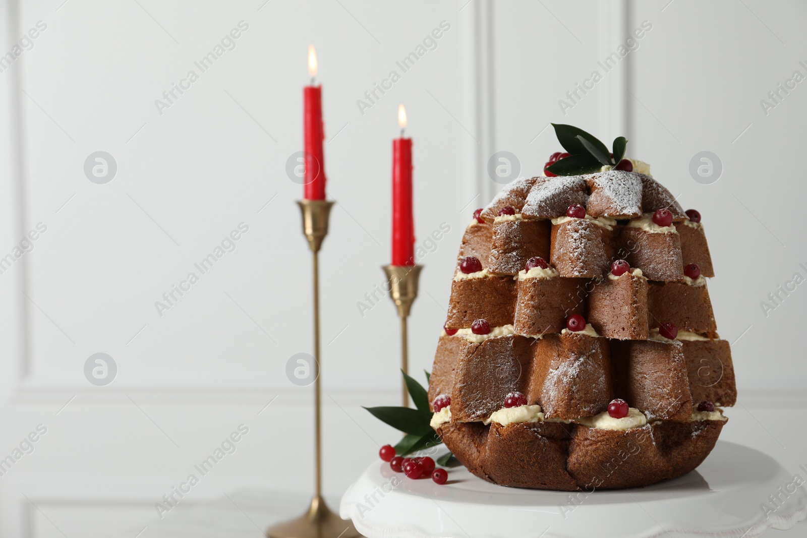 Photo of Delicious Pandoro Christmas tree cake with powdered sugar and berries near festive decor on white table. Space for text