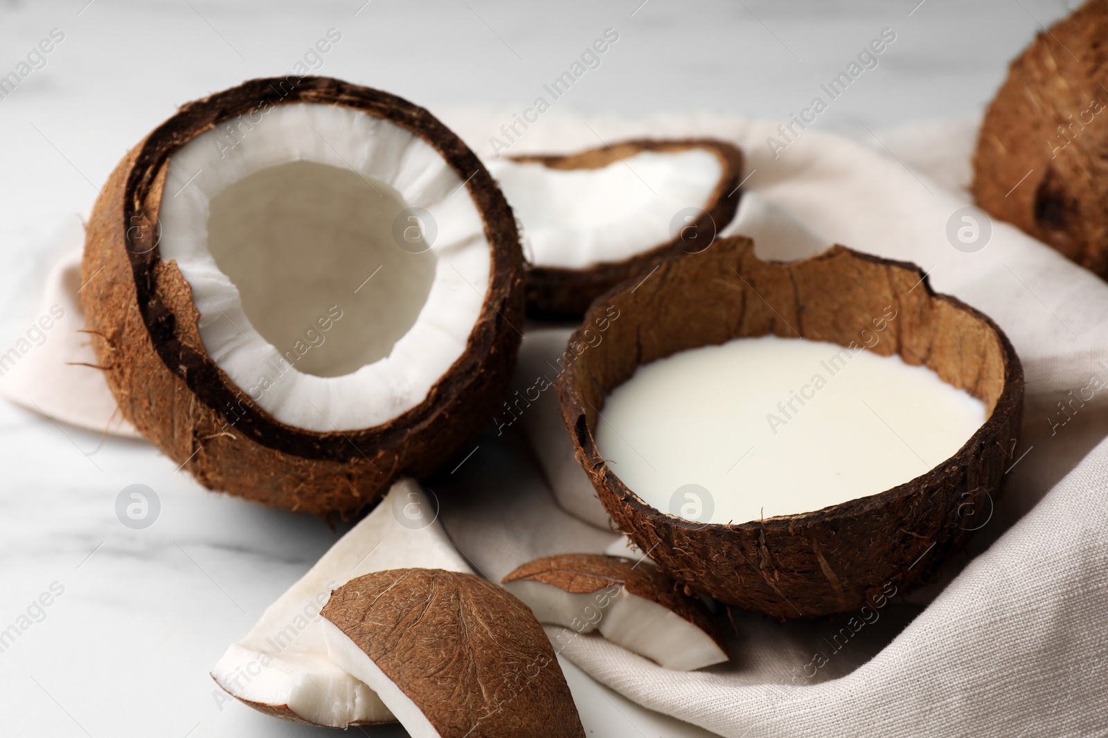 Photo of Delicious vegan milk in coconut and pieces of ripe fruit on white table, closeup