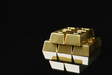 Photo of Shiny gold bars on black background. Space for text