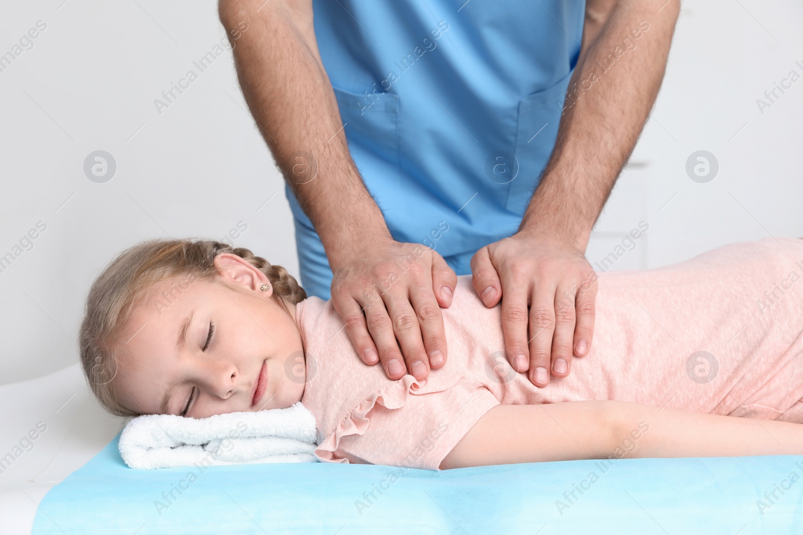 Photo of Orthopedist massaging child's back in clinic, closeup. Scoliosis treatment
