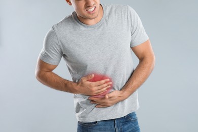 Man suffering from liver pain on grey background, closeup