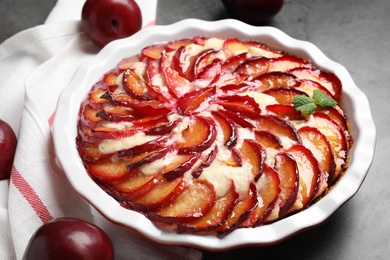 Photo of Delicious cake with plums on grey table, closeup