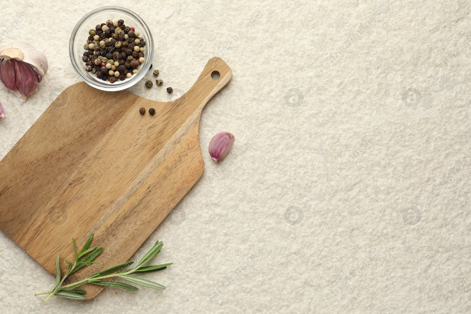 Photo of Cutting board, garlic, pepper and rosemary on white textured table, flat lay. Space for text