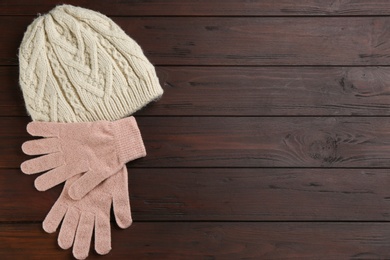 Photo of Stylish gloves and hat on wooden background, flat lay. Space for text