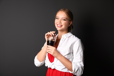 Photo of Young woman with glass of cola on black background. Refreshing drink