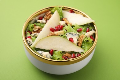 Photo of Delicious pear salad in bowl on green background, closeup