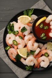 Photo of Tasty boiled shrimps with cocktail sauce, chili, parsley and lemon on grey wooden table, top view