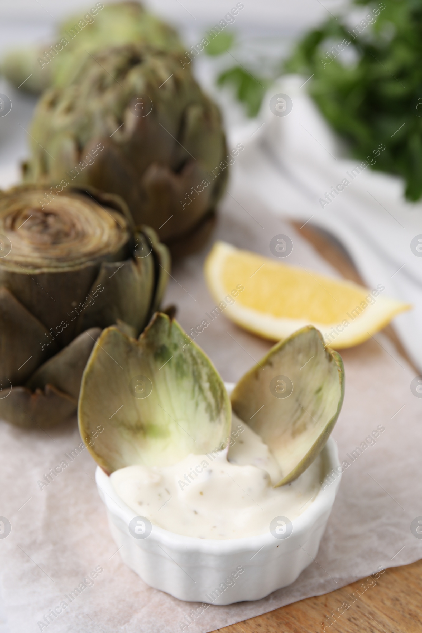 Photo of Delicious cooked artichoke with tasty sauce on table, closeup