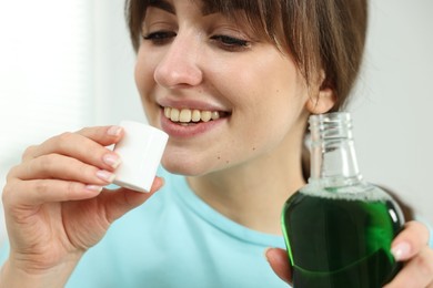 Young woman using mouthwash on light background, closeup