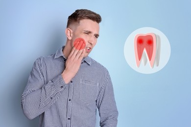 Image of Young man suffering from toothache on light blue background