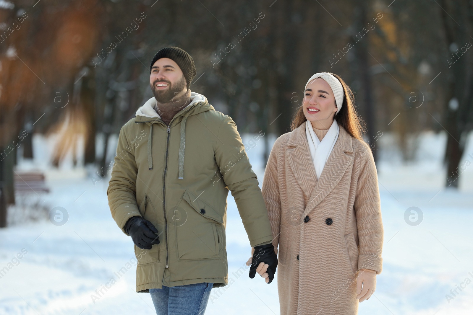 Photo of Beautiful happy couple walking in snowy park on winter day