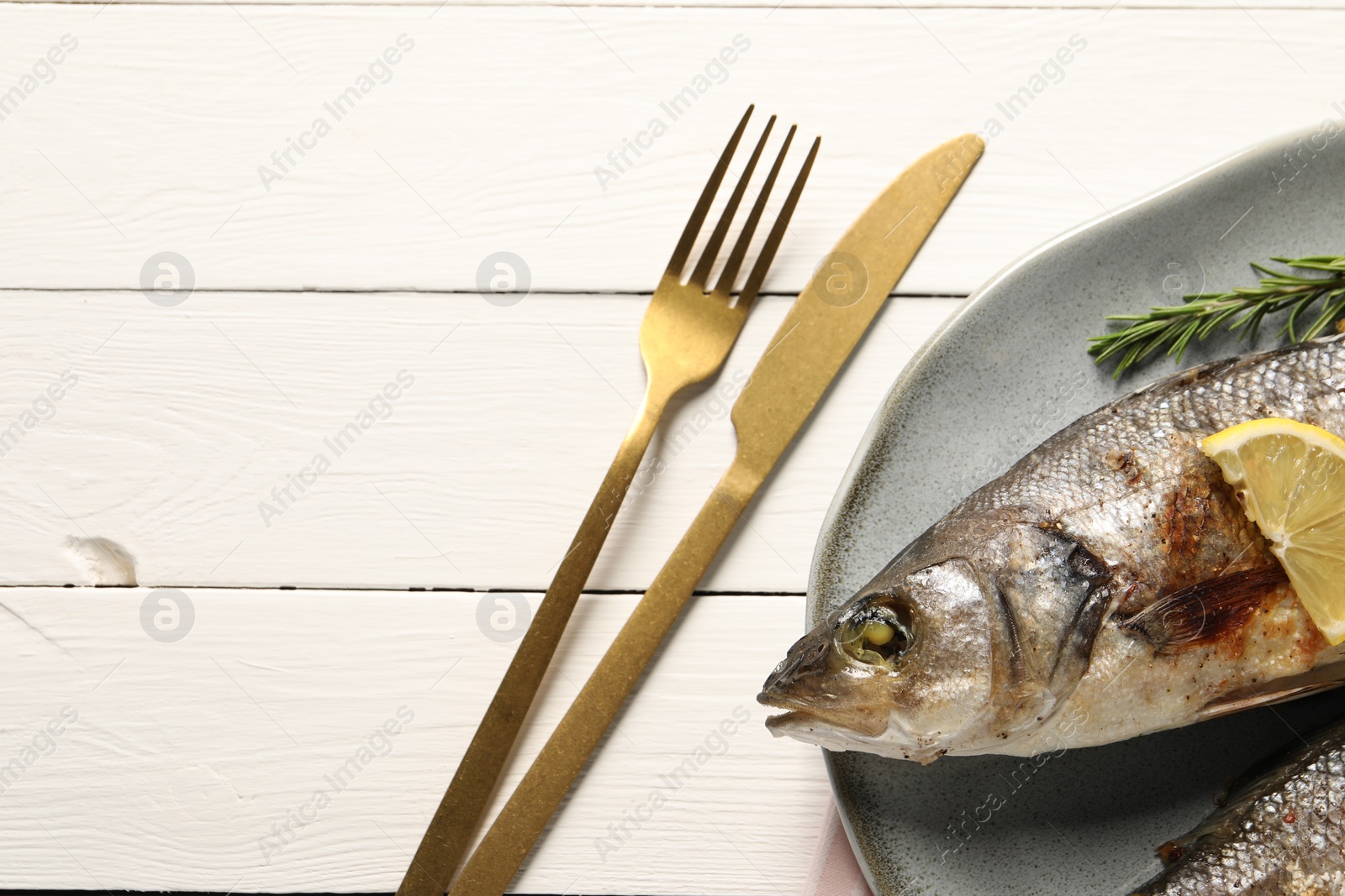 Photo of Delicious baked fish served on white wooden table, top view. Space for text