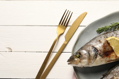 Delicious baked fish served on white wooden table, top view. Space for text