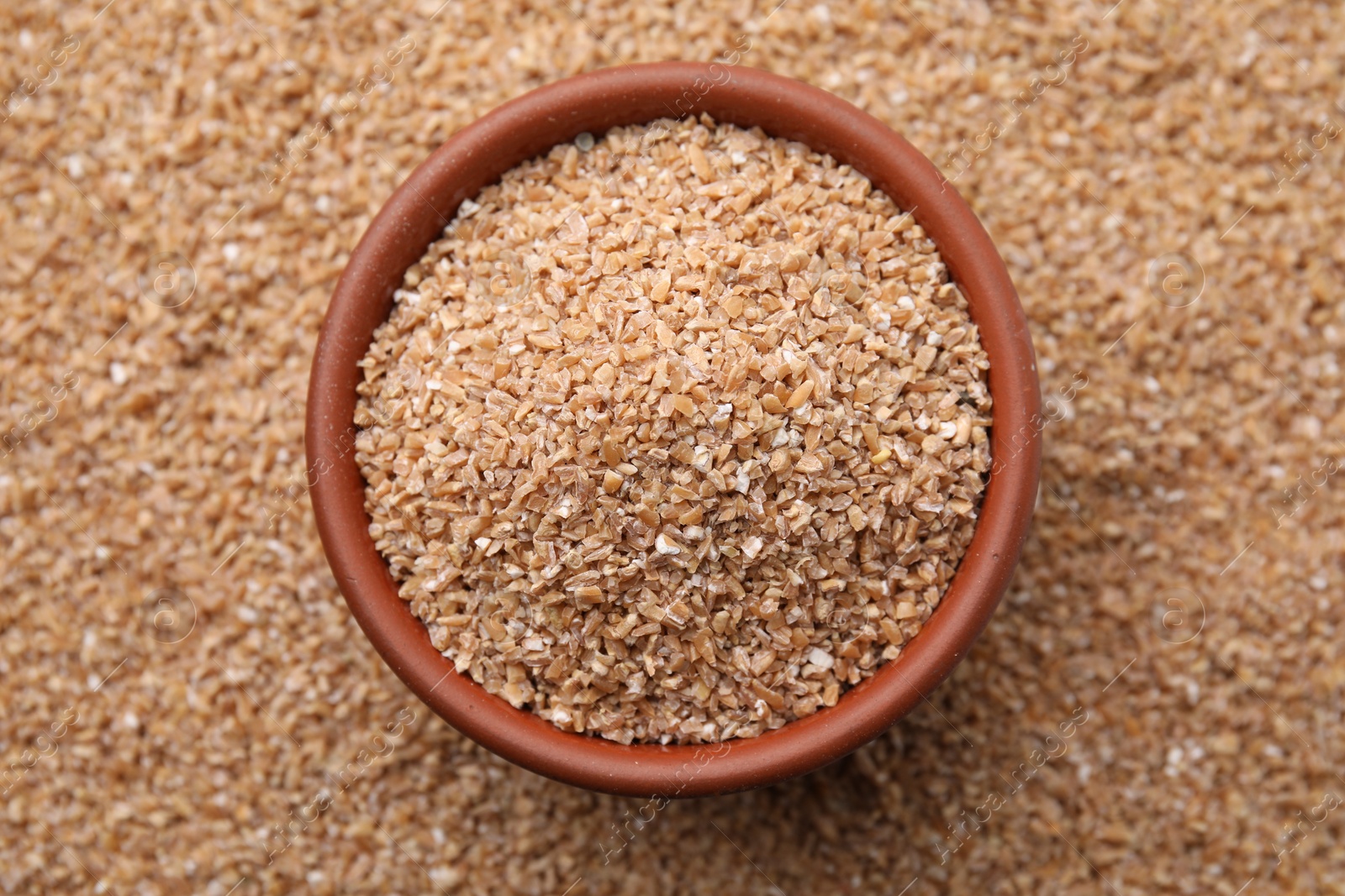 Photo of Bowl and dry wheat groats, top view