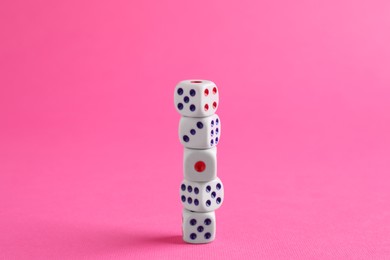 Many stacked game dices on pink background