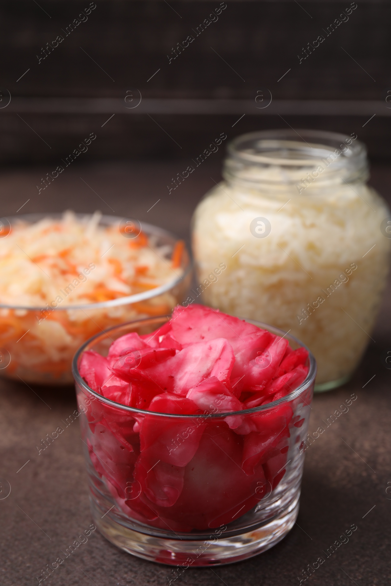 Photo of Delicious sauerkraut prepared according to different recipes on brown table, closeup