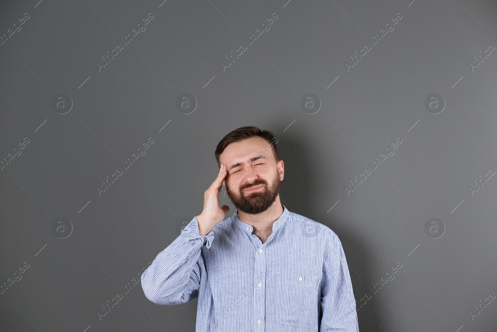 Photo of Portrait of handsome bearded man suffering from headache on color background