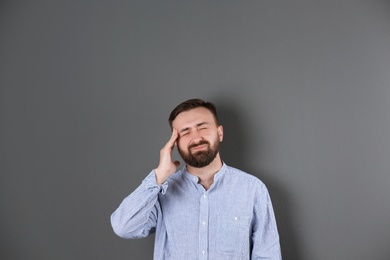 Photo of Portrait of handsome bearded man suffering from headache on color background