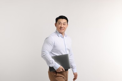 Photo of Portrait of happy man with laptop on light background