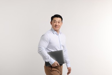 Portrait of happy man with laptop on light background