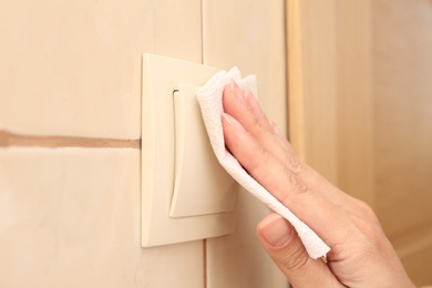 Photo of Woman using tissue paper to switch on light indoors, closeup