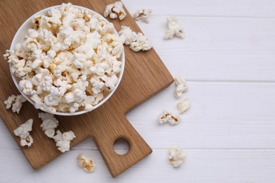 Tasty popcorn on white wooden table, flat lay. Space for text