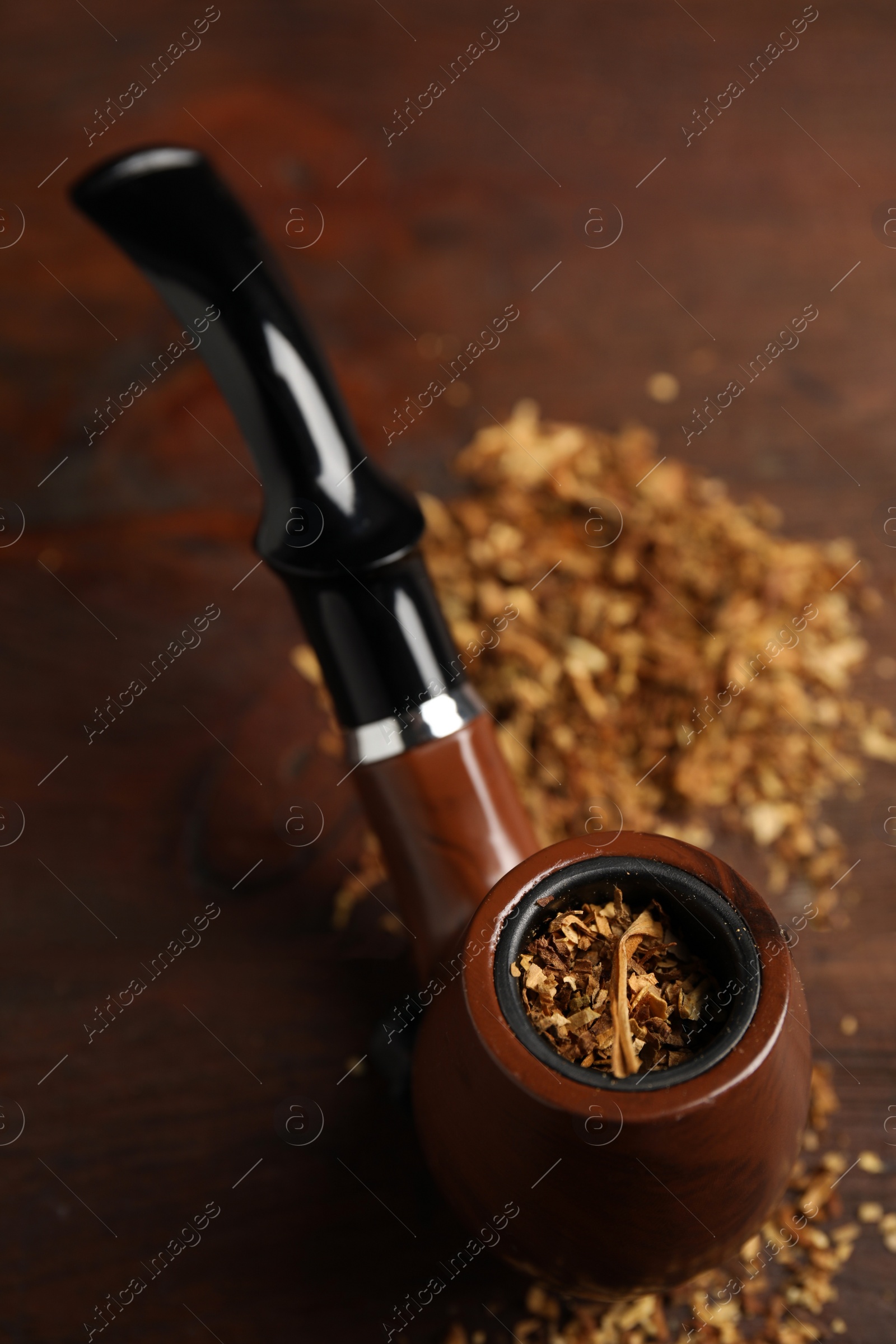 Photo of Smoking pipe with tobacco on wooden table, above view