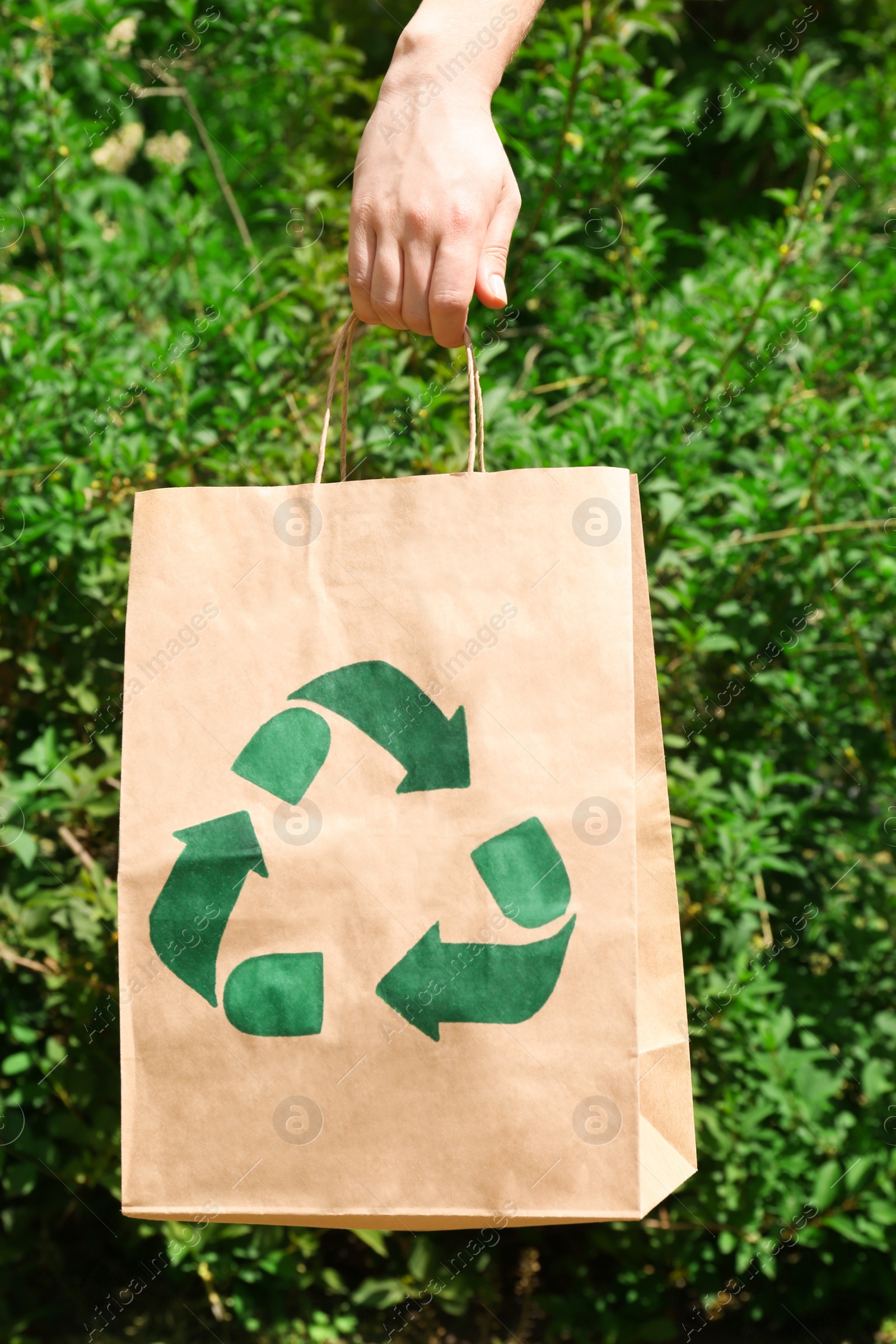 Photo of Woman holding paper bag with recycling symbol outdoors, closeup