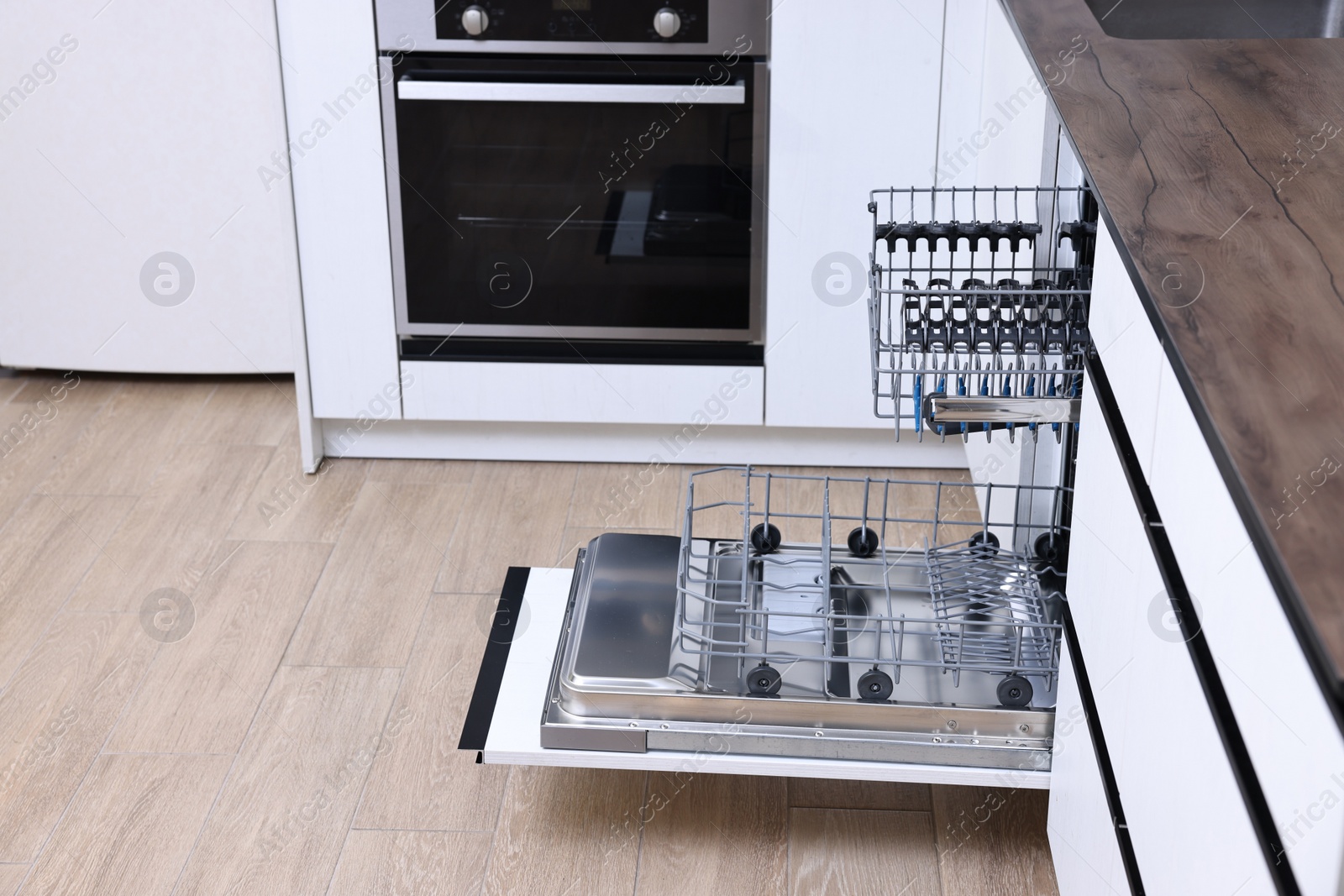 Photo of Open clean empty dishwasher in kitchen. Home appliance