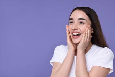 Photo of Portrait of happy surprised woman on violet background. Space for text