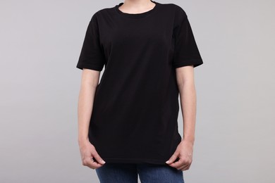 Photo of Woman in stylish black t-shirt light grey on background, closeup