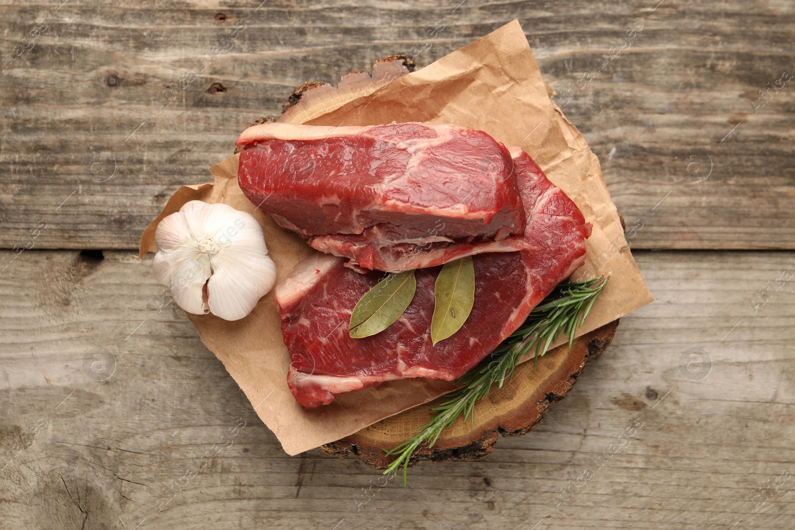 Photo of Pieces of raw beef meat and spices on wooden table, top view