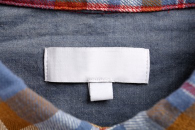 Photo of Blank clothing label on colorful apparel, top view