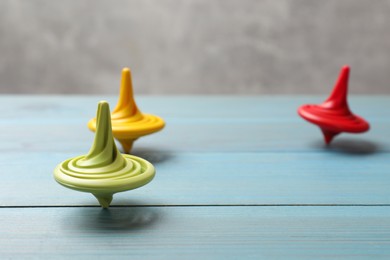 Bright spinning tops on light blue wooden table, closeup